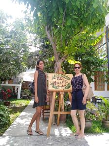 two women standing in front of a wooden chair at El Huerto Hostel in Ica