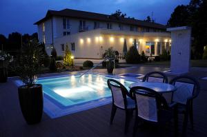 ein Schwimmbad mit Stühlen und einem Tisch und ein Gebäude in der Unterkunft Garden Hotel Wellness és Konferencia in Szolnok