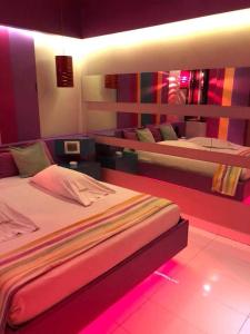 ブエノスアイレスにあるOrigen Hotel -Motel-のベッドルーム1室(ピンクの照明付きのベッド2台付)