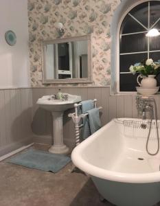 a bathroom with a tub and a sink and a mirror at Ballyginniff Farm House in Crumlin