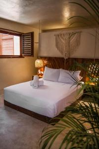 a bedroom with a large white bed with a plant at ALCOBAS DEL MAR in Holbox Island