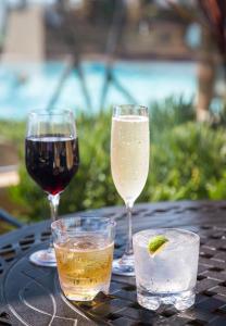 three glasses of wine and a drink on a table at Pacific Terrace Hotel in San Diego