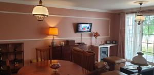 een woonkamer met een tafel en een tv aan de muur bij Casa da Quinta in Funchal