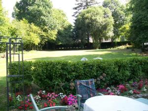 un giardino con tavolo, sedie e fiori di Stone Cottage a Ménéac