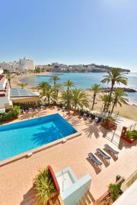 una piscina junto a una playa con palmeras en Apartamentos Lido, en Ibiza