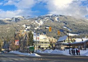 un grupo de personas de pie en una intersección de la calle en la nieve en Village Gate House by Whiski Jack, en Whistler