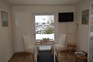 d'une salle à manger avec une table, des chaises et une fenêtre. dans l'établissement Glockenturmblick, à Sankt-Andreasberg