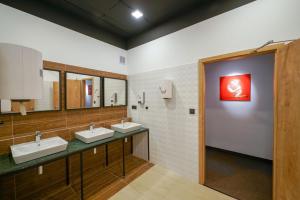 Baño con 3 lavabos y una pintura roja en la pared en CHORS like a hotel - 1st World NFT Block & Art Capsule Hostel MetaCHORS, en Bratislava