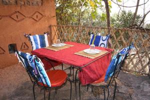 a table with a red table cloth and chairs on a balcony at Riad Atlas Berbère in Boumalne Dades
