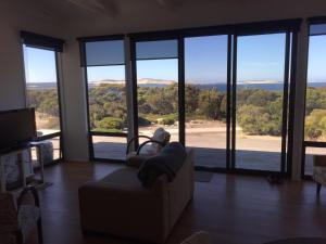 a living room with a couch and large glass windows at Wallaby Retreat in Kingscote