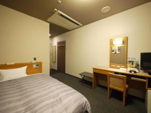 Cette chambre comprend un lit, un bureau et une télévision. dans l'établissement Route Inn Grantia Komaki, à Komaki