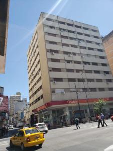 un taxi amarillo frente a un gran edificio en Departamento temporal Colon 401 en Córdoba