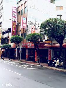 eine Stadtstraße mit Bäumen und Schildern an Gebäuden in der Unterkunft Meets Happy Hotel in Yonghe