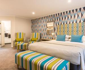 um quarto de hotel com duas camas e duas cadeiras em ASURE Destiny on Fitzherbert Motel em Palmerston North
