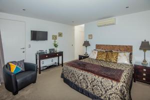 a bedroom with a bed and a chair and a television at Tarlton's Lodge in Paihia