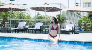 una mujer en bikini sentada en una piscina en Muong Thanh Luxury Ha Nam en Phủ Lý