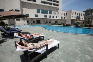 two women laying on lawn chairs by a swimming pool at Muong Thanh Luxury Ha Nam in Phủ Lý
