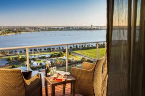 een balkon met een tafel en stoelen en uitzicht op het water bij Fraser Suites Perth in Perth