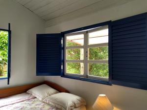 a bedroom with blue shuttered windows and a bed at Chalés Del'Minas in Passa Quatro