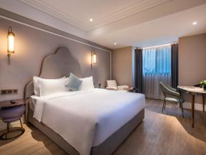 a hotel room with a large bed and a desk at Mercure Shanghai Global Harbour in Shanghai +34 photos
