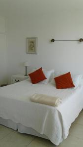 Una cama blanca con dos almohadas rojas. en Peninsula en Punta del Este