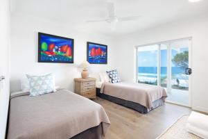 a bedroom with two beds and a window with the ocean at 2 Arakoon Crescent, Sunshine Beach in Noosa Heads