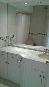 La salle de bains blanche est pourvue d'un lavabo et d'un miroir. dans l'établissement Peninsula, à Punta del Este