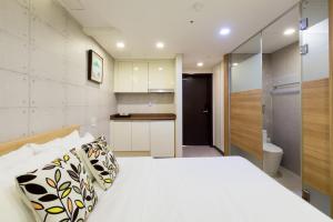 a bedroom with a white bed and a bathroom at Vistacay Hotel Worldcup in Seogwipo