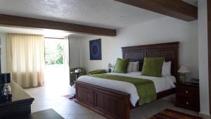 um quarto com uma cama grande e almofadas verdes em Hotel Las Puertas de Tepoztlan em Tepoztlán