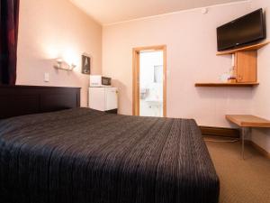 a hotel room with a bed and a flat screen tv at Masonic Hotel in Palmerston North