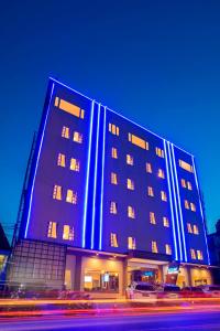 un grand bâtiment bleu avec des voitures garées devant lui dans l'établissement Zoom Hotel Mulawarman, à Samarinda