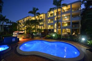 a swimming pool in front of a building at night at Argosy On The Beach in Clifton Beach