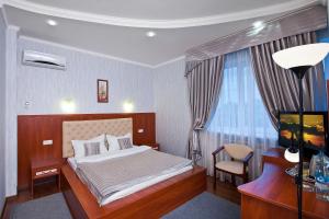 1 dormitorio con cama, escritorio y silla en Aureliu Hotel, en Krasnodar