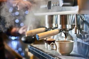 een koffiezetapparaat is het maken van een kopje koffie bij Mackay Oceanside Central Hotel Official in Mackay
