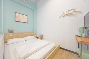 a bedroom with a white bed and blue walls at OX Suites in Kaohsiung