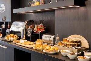 - une boulangerie avec du pain et des viennoiseries sur un comptoir dans l'établissement Best Western Hôtel Journel Paris Sud, à Ris-Orangis