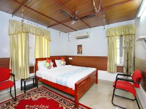 een slaapkamer met een bed en een rode stoel bij Honolulu Home in Cochin
