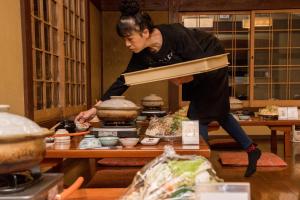 a woman standing in a kitchen preparing food at Kyo no Minshuku Ohara no Sato in Kyoto