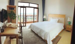 a bedroom with a white bed and a balcony at Sanya Haitangwan Shang Gong Yuan She Wellness Resort Villa in Sanya