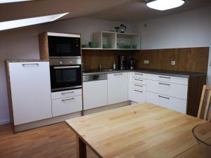 a kitchen with white cabinets and a wooden table at Altes Warmbad Wolgast in Wolgast