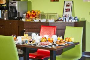 a table with plates of food and fruit on it at Enzo Hotels Thionville by Kyriad Direct in Thionville