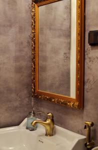 a bathroom sink with a gold faucet and a mirror at Putiikkihotelli Kemi 1932 in Kemi