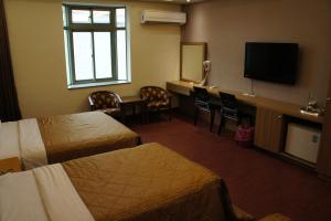a hotel room with two beds and a flat screen tv at Paris Motel in Mailiao