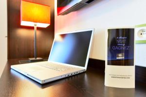 a laptop computer sitting on a desk next to a book at Enzo Hotels Thionville by Kyriad Direct in Thionville