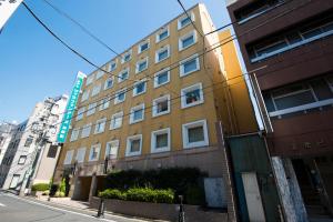 Hotel Villa Fontaine Tokyo-Jimbocho في طوكيو: مبنى اصفر على شارع المدينة