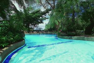 ein großer Pool mit blauem Wasser und Bäumen in der Unterkunft Amboseli Serena Safari Lodge in Amboseli-Nationalpark