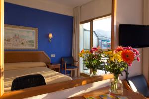 a bedroom with a bed and a table with flowers at Hotel Colón in Benidorm