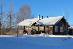 a wooden house with a snow covered roof at Marjakartano Hussola in Karttula