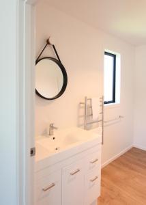 a white bathroom with a sink and a mirror at 4 - Charming Space, Just a Stone Throw from Central Wanaka in Wanaka