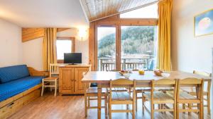 sala de estar con mesa, sillas y sofá en Vacancéole - Résidence Les Chalets et Balcons De La Vanoise, en La Norma